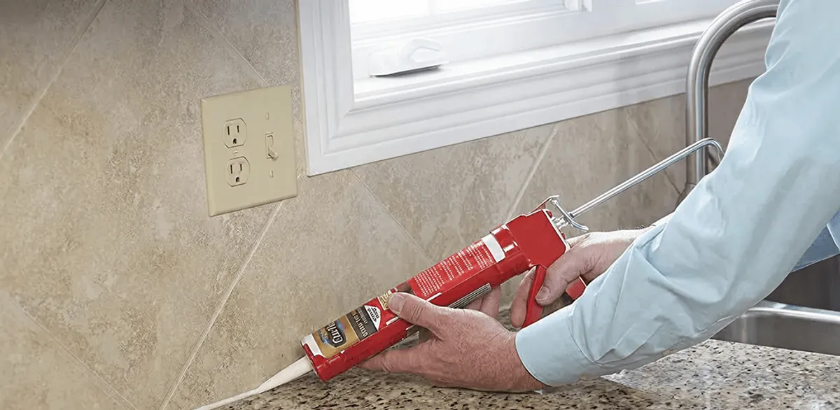 Handyman applying caulk along a kitchen backsplash and countertop seam in Aurora, CO